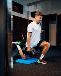 a man doing squats with dumbbells in a gym