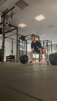 a man squatting with a barbell in a gym